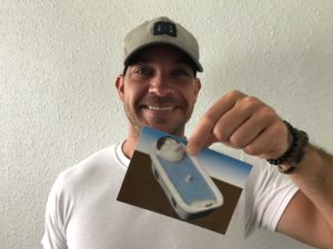 man smiling with a postcard of a man in the bathtub