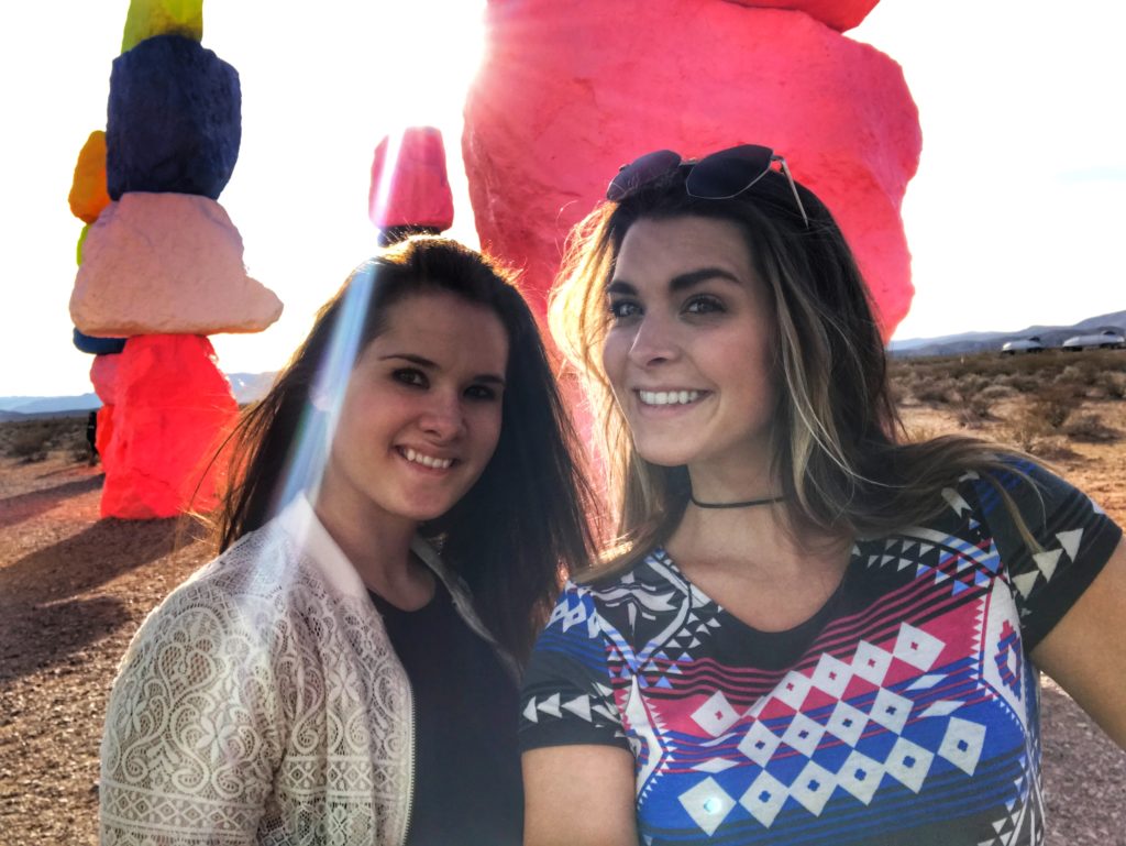 friends smiling next to the Seven Magic Mountains