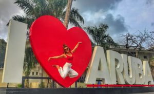 woman jumping at the I heart Aruba sign