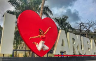 woman jumping at the I heart Aruba sign