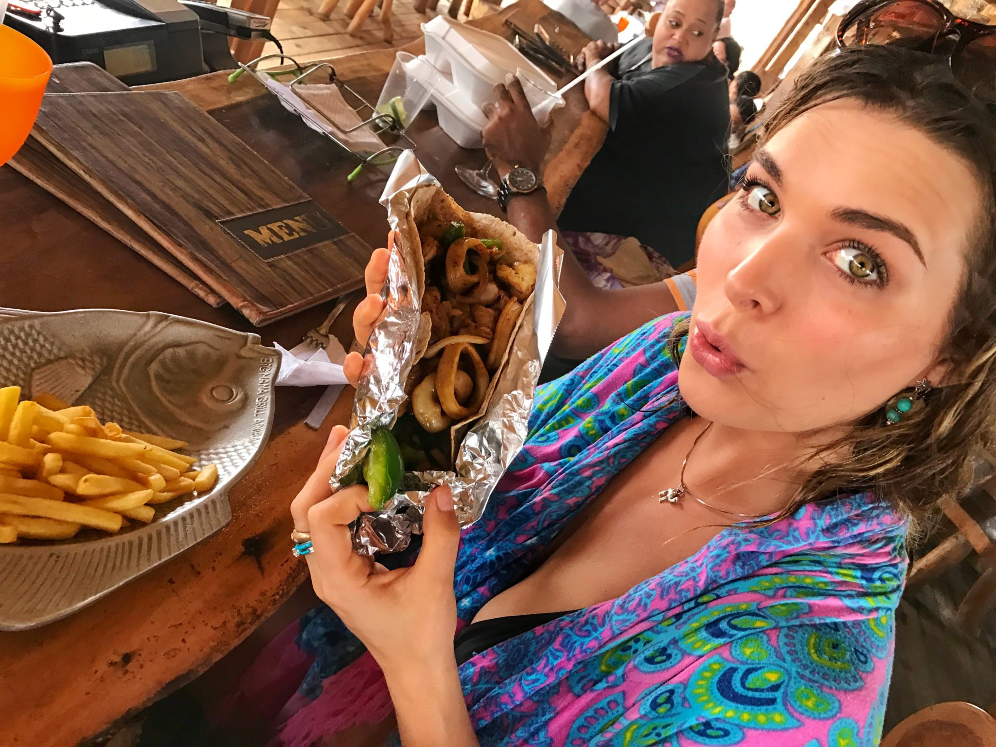 woman eating a large taco at baby beach in aruba
