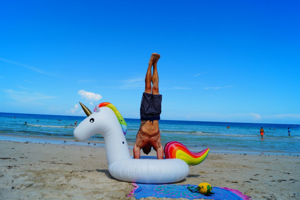 man doing handstand with inflatable unicorn