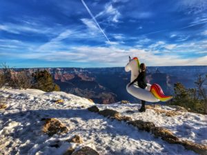 woman holding an inflatable unicorn at the Grand Canyon during winter